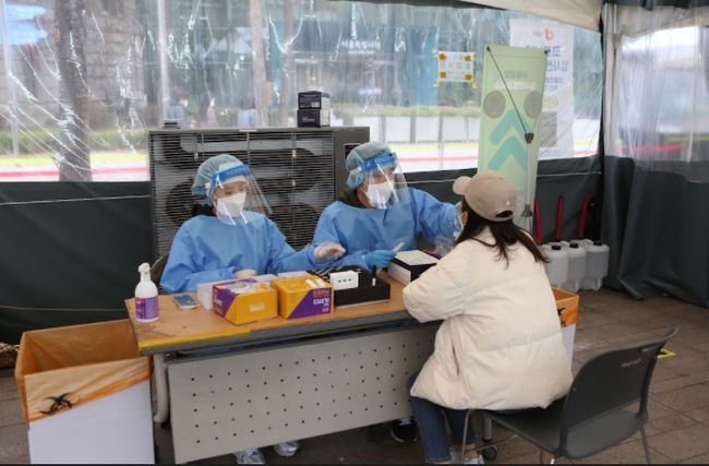 정부는 코로나19 감염병 등급을 1급에서 2급으로 하향하는 방안을 논의 중인 것으로 전해졌다. 서울시청 선별검사소에서 한 시민이 코로나19 검사에 응하고 있다.