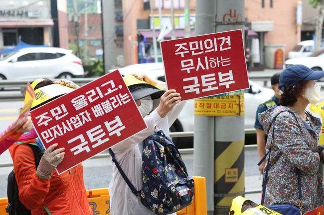 어명소 국토교통부 제2차관은 1월 27일 15시 광명서울고속도로 건설현장을 찾아 공사 진행상황을 점검하고 관계자들을 격려했다. 사진은 지난 2019년 5월30일 광명서울고속도로 온수터널 구간의 주민들이 학교 밑 발파, 수직구 강행 등 해당 공사의 문제점을 지적하며 국토부에 항의하는 모습이다.