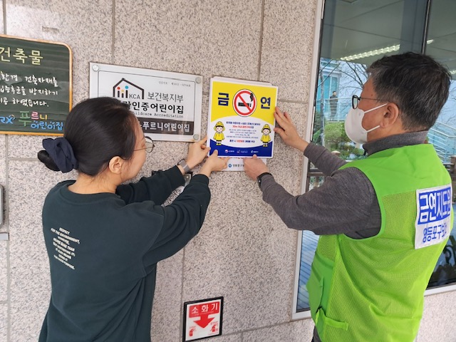 금연지도원들이 금연구역 신규 및 확대 지정 구역과 관련하여 계도 및 안내하고 있는 모습