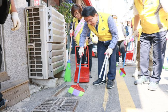 문헌일 구로구청(사진 가운데)이 5월 31일 구로2동 빗물받이에 쌓인 쓰레기를 청소하고 있다.